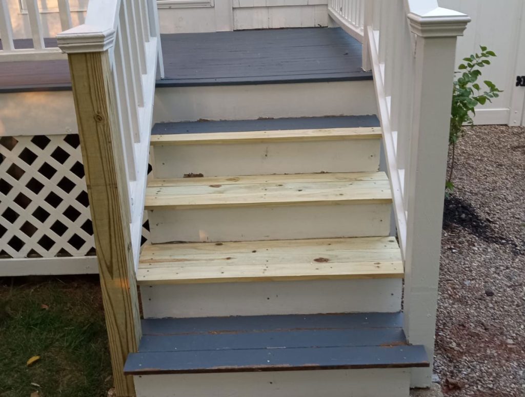Exterior stairs with rotted treads and post replaced with fresh wood, before painting.